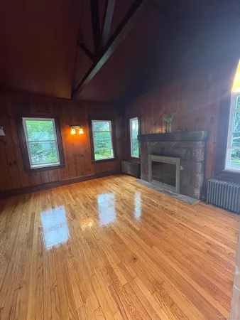 an empty room with wooden floor fireplace and windows