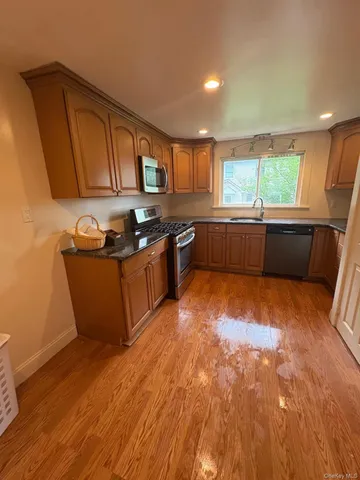 a kitchen with stainless steel appliances granite countertop a sink a stove a refrigerator cabinets and wooden floor