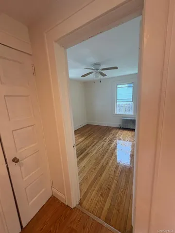 an empty room with wooden floor cabinet and windows