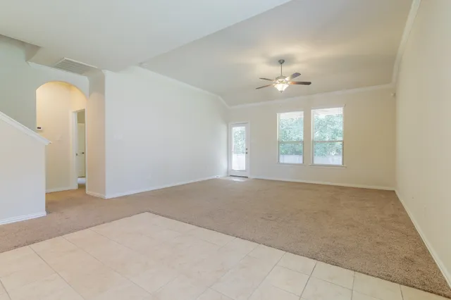 an empty room with windows and ceiling fan