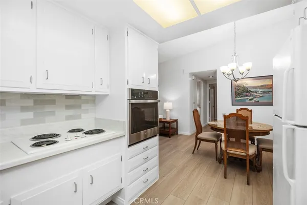 a kitchen with stainless steel appliances a dining table chairs stove refrigerator and cabinets