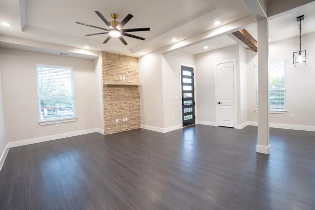 a view of an empty room with window and wooden floor