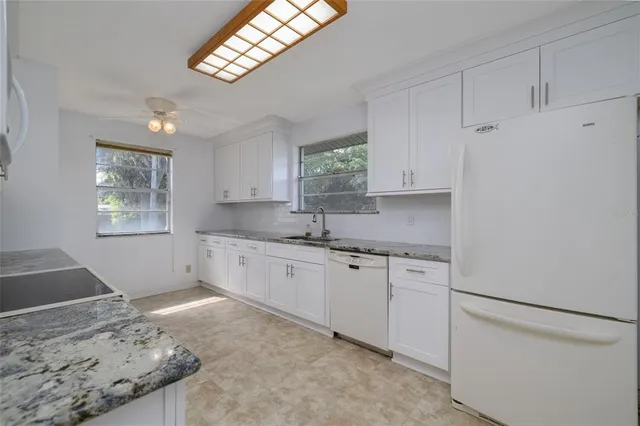 a kitchen with granite countertop white cabinets and white appliances