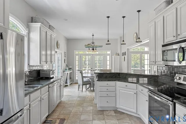 a large kitchen with granite countertop a stove a sink a refrigerator and white cabinets