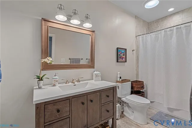 a bathroom with a toilet a sink a mirror a vanity and window