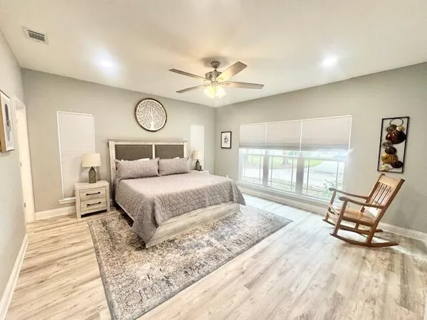 a bedroom with a bed a chair and a large window