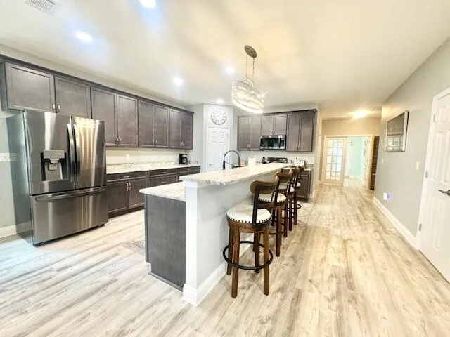 a kitchen with stainless steel appliances a refrigerator a stove a sink dishwasher and white cabinets with wooden floor