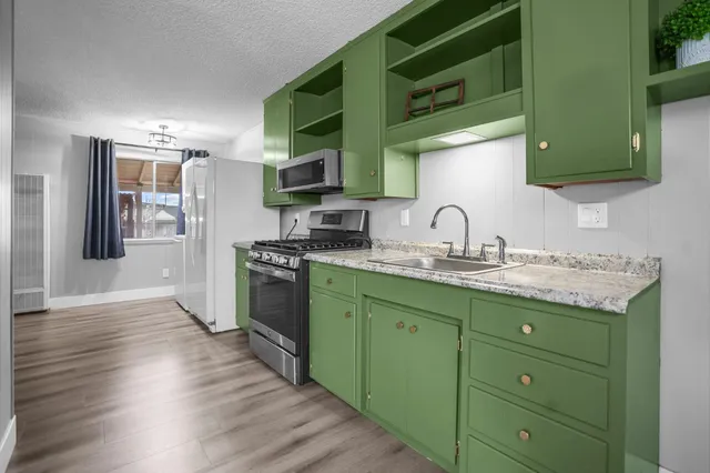 a kitchen with granite countertop a sink cabinets and stainless steel appliances