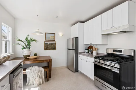 a kitchen with stainless steel appliances a stove a sink a refrigerator and a cabinets