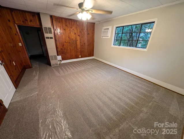 an empty room with chandelier fan and windows