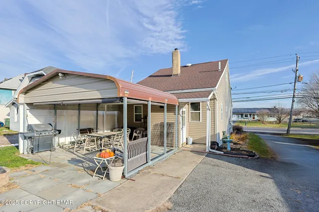 a view of a patio with table and chairs near a barbeque