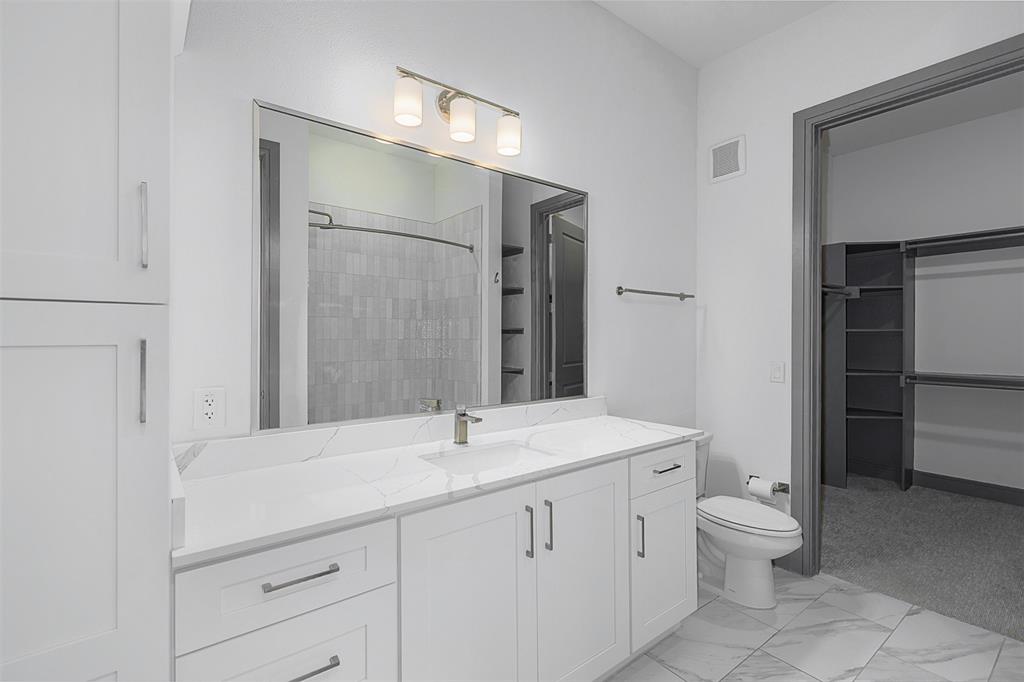 2700 Old Denton Road, Unit 1044 Carrollton, TX 75007 - Photo 7 of 33 Bathroom vanity featuring a single sink, light stone-finish countertop, and white cabinetry
