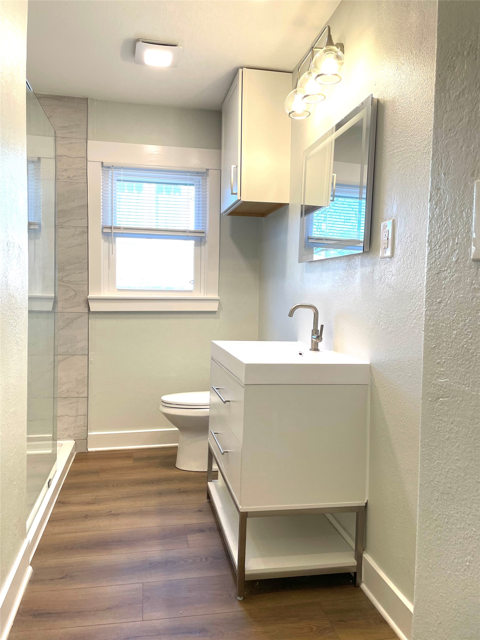 807 East Riverside Drive, Unit A Austin, TX 78704 - Photo 14 of 29 Full bath featuring vanity, a textured wall, dark wood-style flooring, and a tile shower