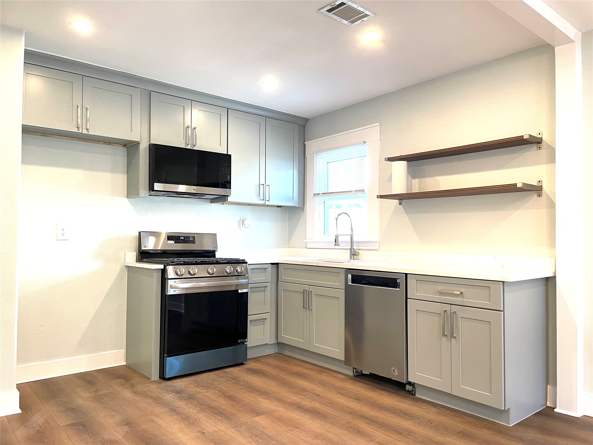 807 East Riverside Drive, Unit A Austin, TX 78704 - Photo 5 of 29 Kitchen featuring gray cabinets, stainless steel appliances, open shelves, and dark wood-type flooring