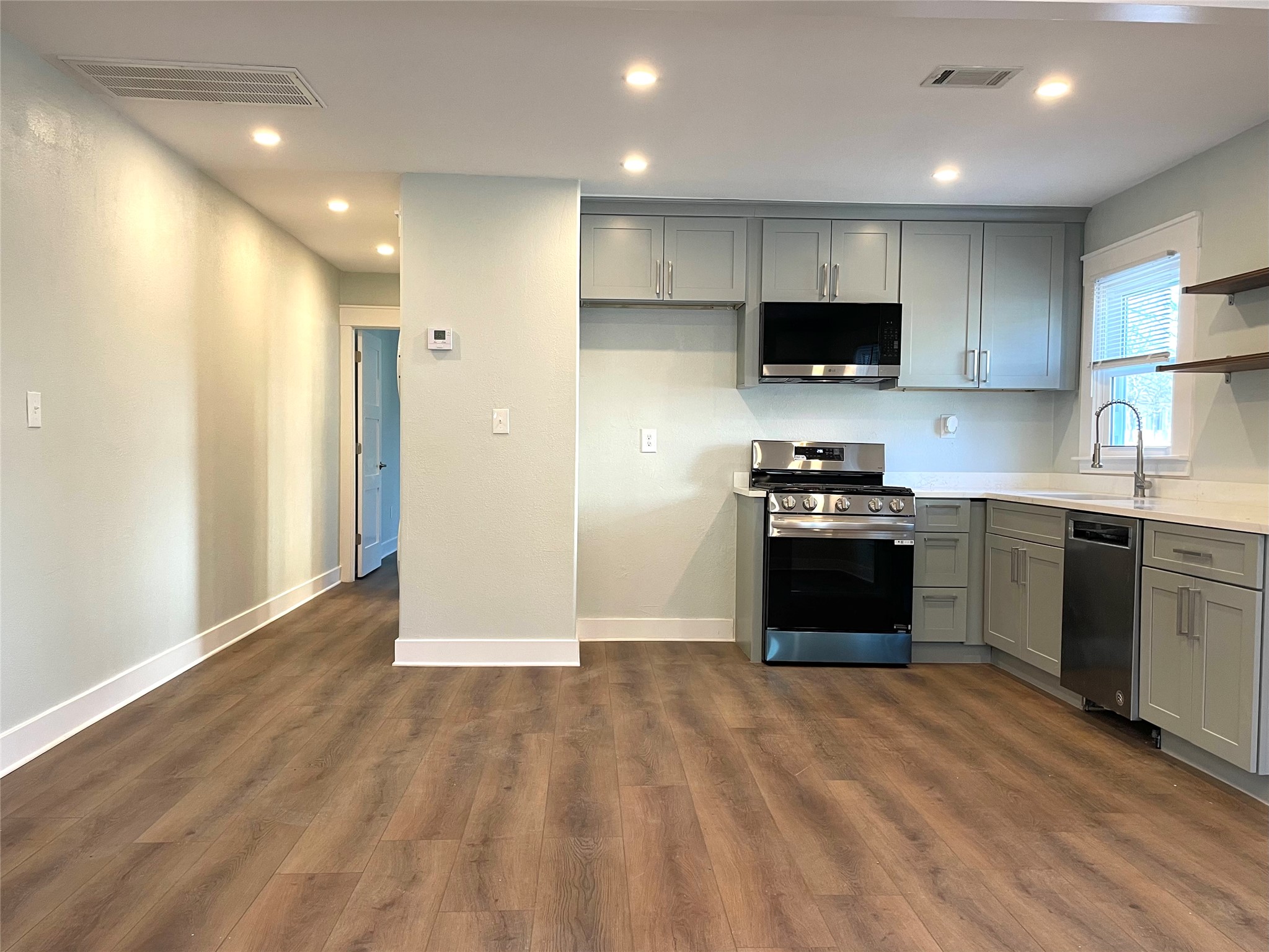 807 East Riverside Drive, Unit A Austin, TX 78704 - Photo 6 of 29 Kitchen featuring gray cabinetry, stainless steel appliances, open shelves, dark wood-type flooring, and recessed lighting