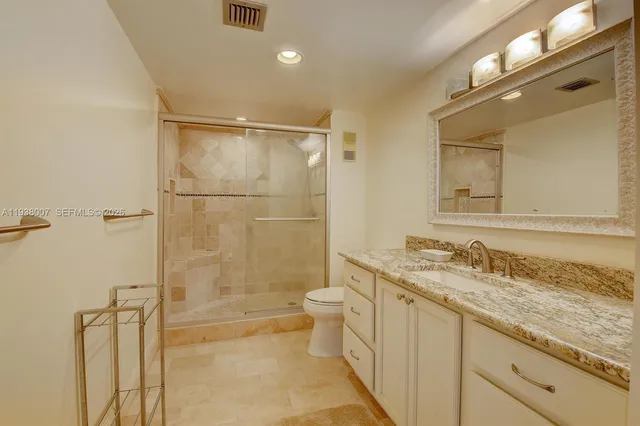 a bathroom with a granite countertop sink toilet and shower