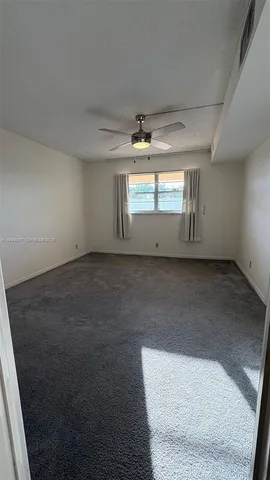 an empty room with a ceiling fan and window