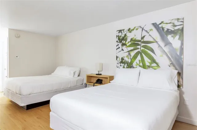 a bedroom with two beds and a painting on the wall