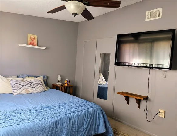 a bedroom with a bed and a flat tv screen on the dresser