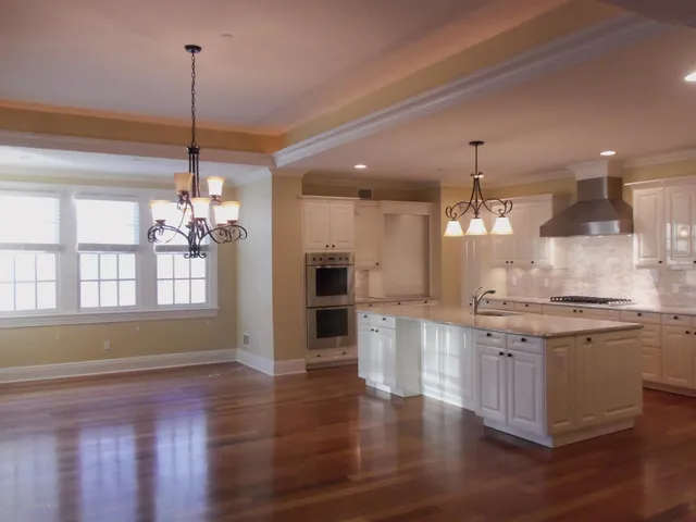 a kitchen with stainless steel appliances granite countertop wooden floors and white cabinets