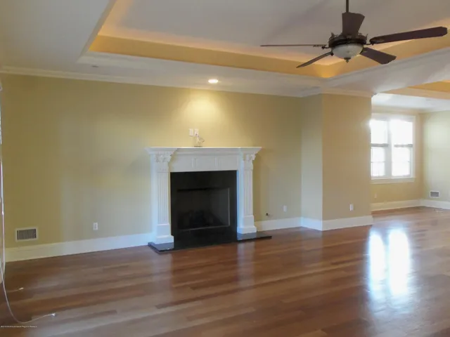 a view of an empty room with wooden floor and a fireplace
