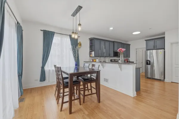 a kitchen with stainless steel appliances kitchen island granite countertop a refrigerator a stove a microwave oven a sink with island and chairs with wooden floor