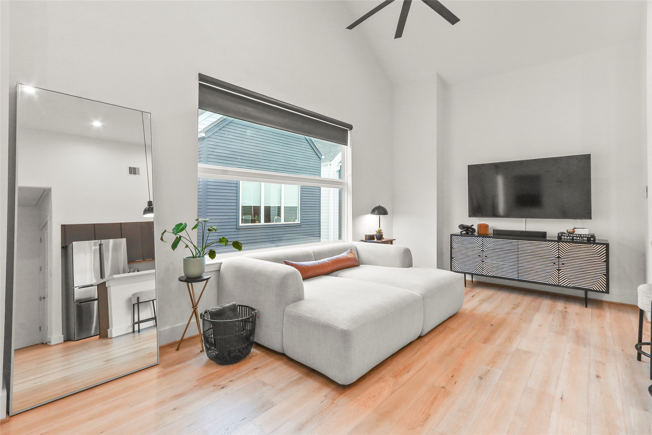 1141 West 17th Street, Unit A Houston, TX 77008 - Photo 4 of 18 Living room featuring high vaulted ceiling, light wood-style flooring, oversized black smart fan, and window treatments