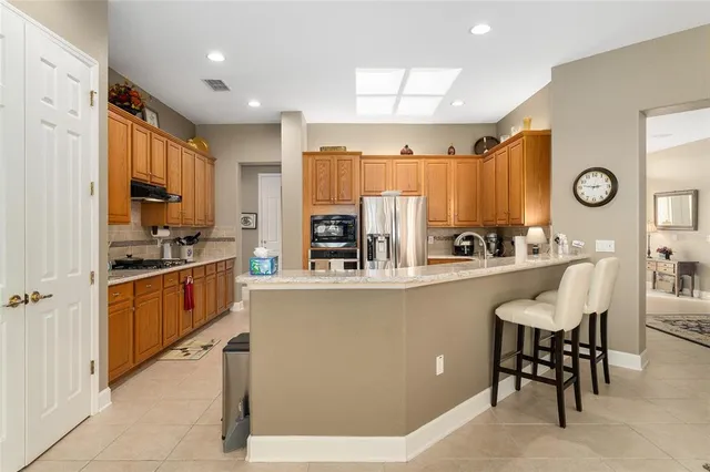 a kitchen with stainless steel appliances granite countertop a stove top oven a sink a dining table and chairs with wooden floor