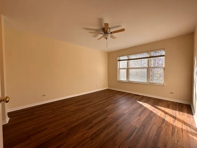 a view of empty room with wooden floor and fan