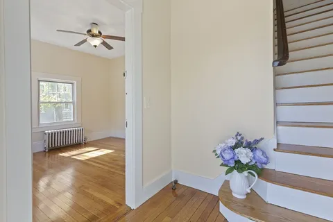 a view of an empty room with wooden floor and a window
