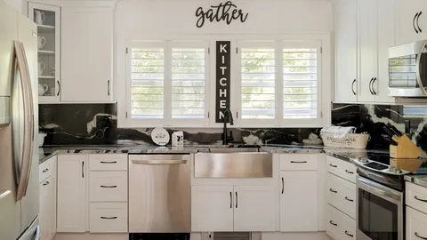 a kitchen with granite countertop a stove a sink and white cabinets