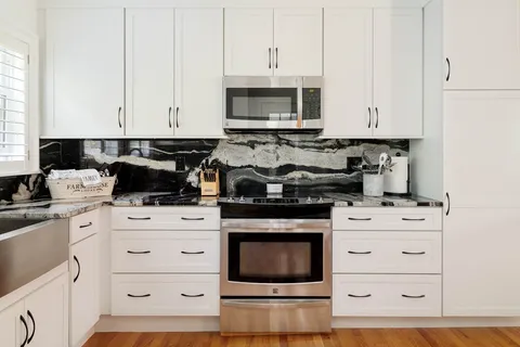 a kitchen with white cabinets and appliances