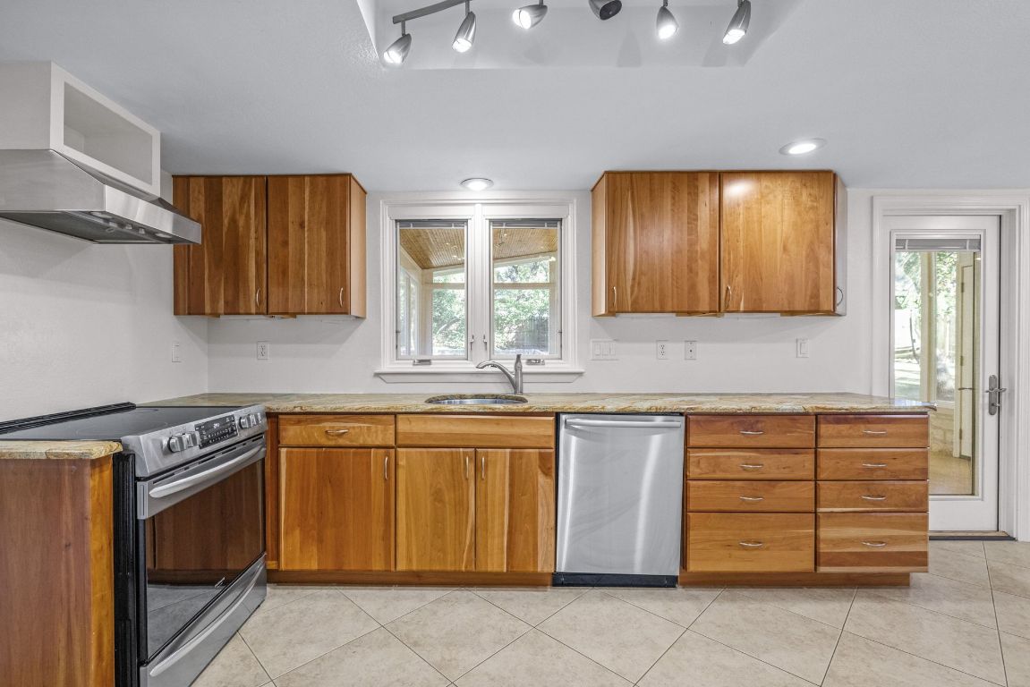 1508 Ben Crenshaw Way Austin, TX 78746 - Photo 11 of 40 a kitchen with stainless steel appliances granite countertop wooden cabinets a sink and a stove