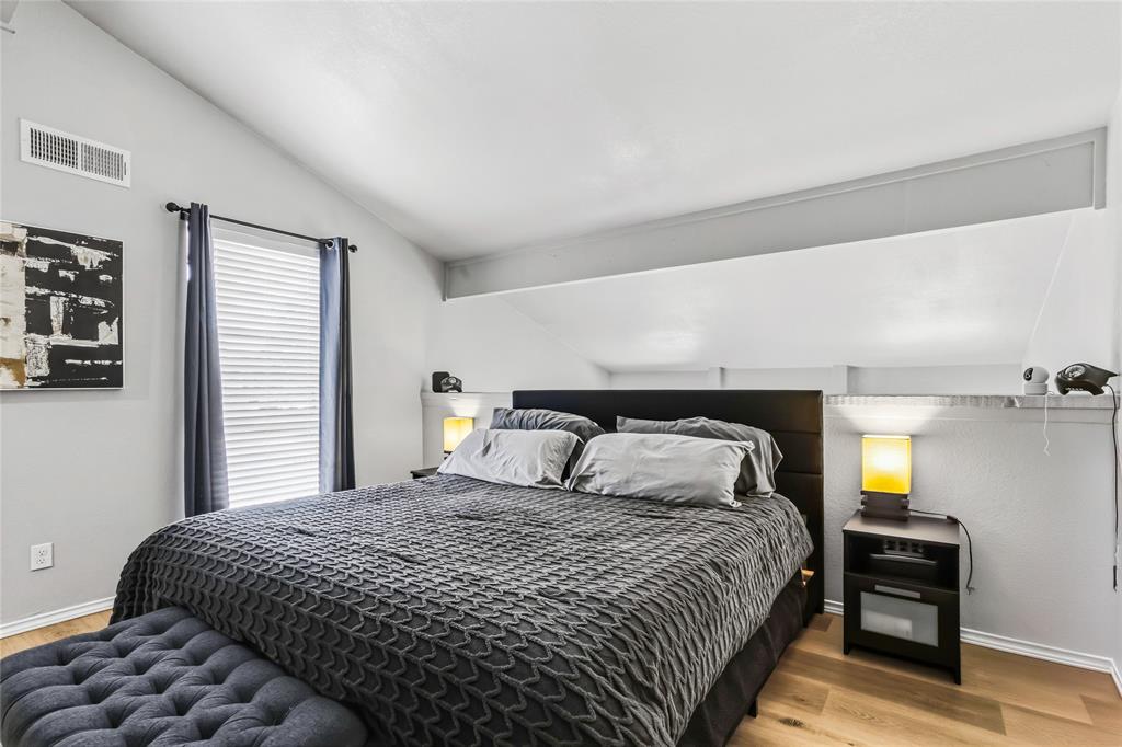 5540 Boca Raton Boulevard, Unit 181 Fort Worth, TX 76112 - Photo 14 of 21 Vaulted ceiling bedroom featuring wood-finish flooring, a window with horizontal blinds, and a built-in wall shelf