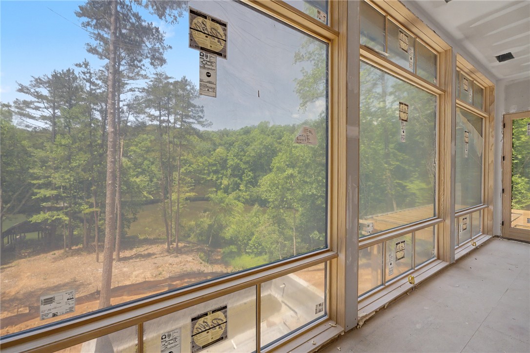 166 Ellenburg Creek Road Sunset, SC 29685 - Photo 8 of 20 Floor-to-ceiling windows frame verdant tree and lake vistas, inviting nature's beauty indoors.