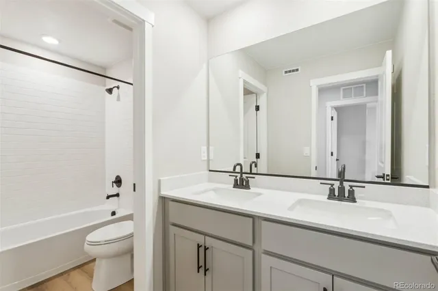 a bathroom with a double vanity sink toilet mirror and shower