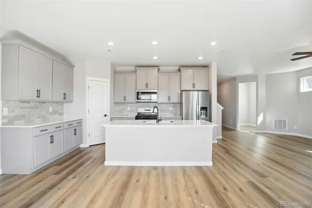 a large white kitchen with kitchen island a sink a stove a refrigerator and white cabinets