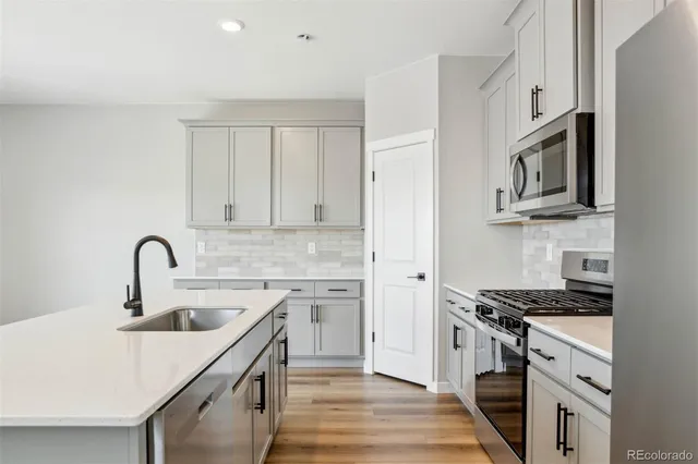 a kitchen with stainless steel appliances granite countertop a sink stove cabinets and refrigerator