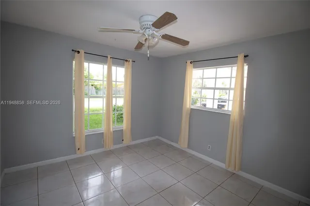an empty room with windows and chandelier fan