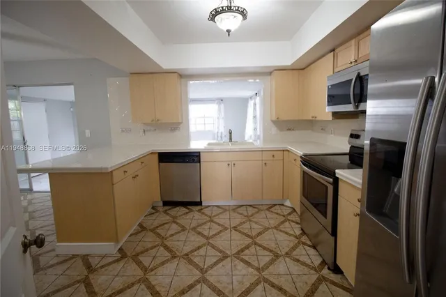 a kitchen with stainless steel appliances a sink a stove a refrigerator cabinets and a window