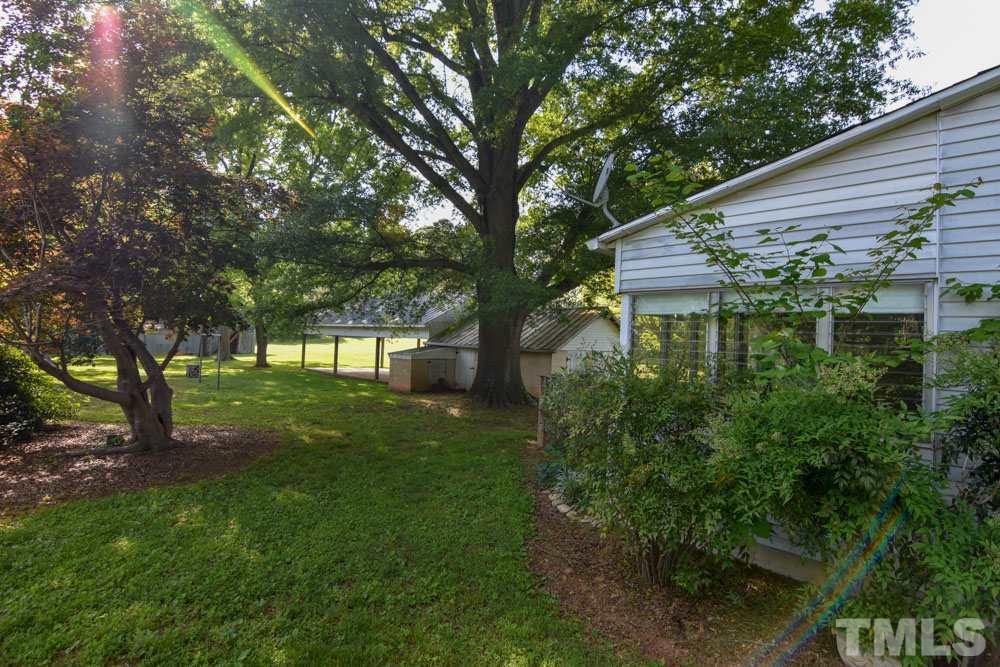 8919 North Roxboro Road Bahama, NC 27503 - Photo 17 of 26 a backyard of a house with plants and large tree