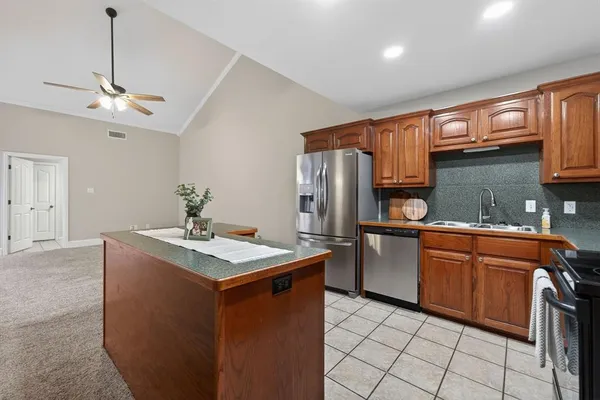 a kitchen with stainless steel appliances granite countertop a sink a stove a refrigerator and island