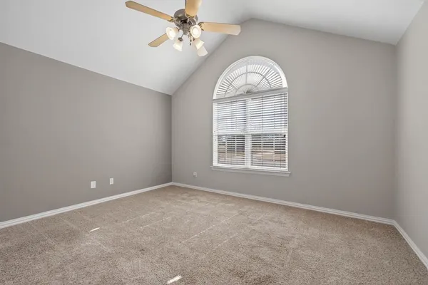 an empty room with a chandelier fan and windows