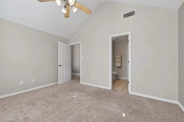 an empty room with a chandelier fan and closet area