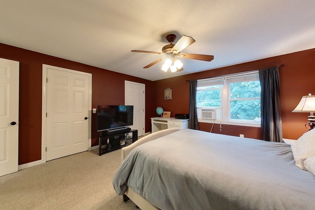 103 Main Street, Unit 16 Pepperell, MA 01463 - Photo 20 of 33 a bedroom with a large bed and a flat tv screen on dresser