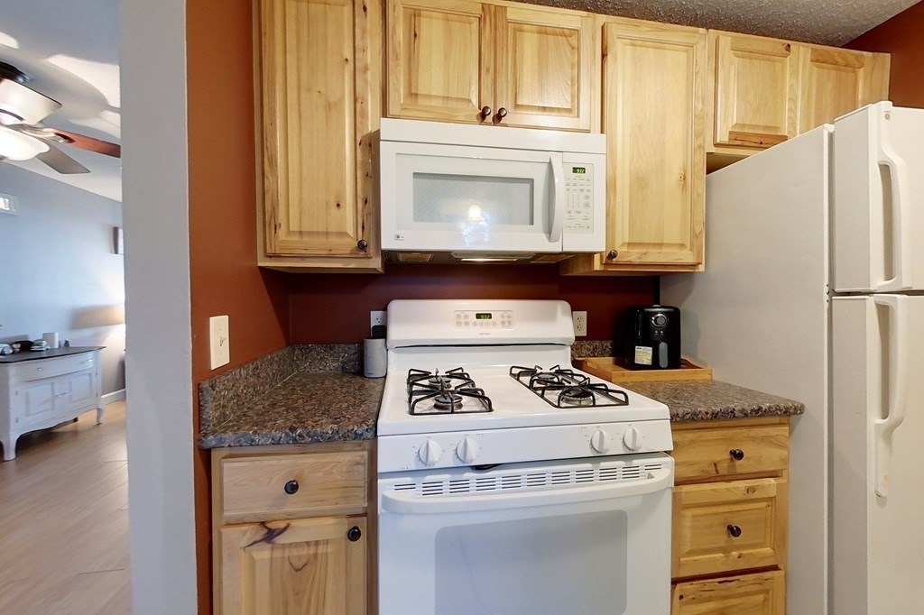 103 Main Street, Unit 16 Pepperell, MA 01463 - Photo 6 of 33 a kitchen with granite countertop a sink stove and refrigerator