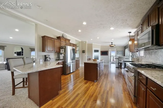 a kitchen with stainless steel appliances granite countertop a refrigerator a stove top oven a sink dishwasher and white cabinets with wooden floor