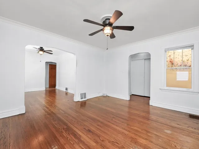 a view of empty room with wooden floor and fan