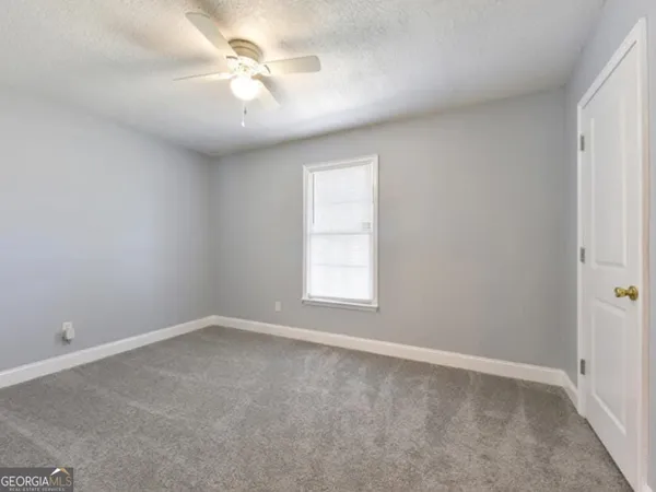 an empty room with a window and a fan