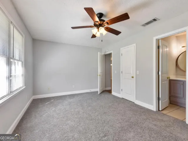 an empty room with windows and fan